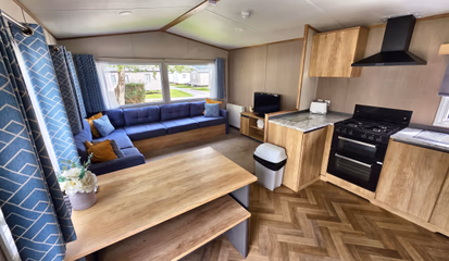 Inside a hire caravan, showing the lounge seating, dining table and fitted kitchen