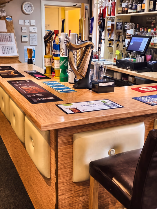 The bar at the Tow-Bar, with optics and bottles on the back shelf and drink mats along the counter